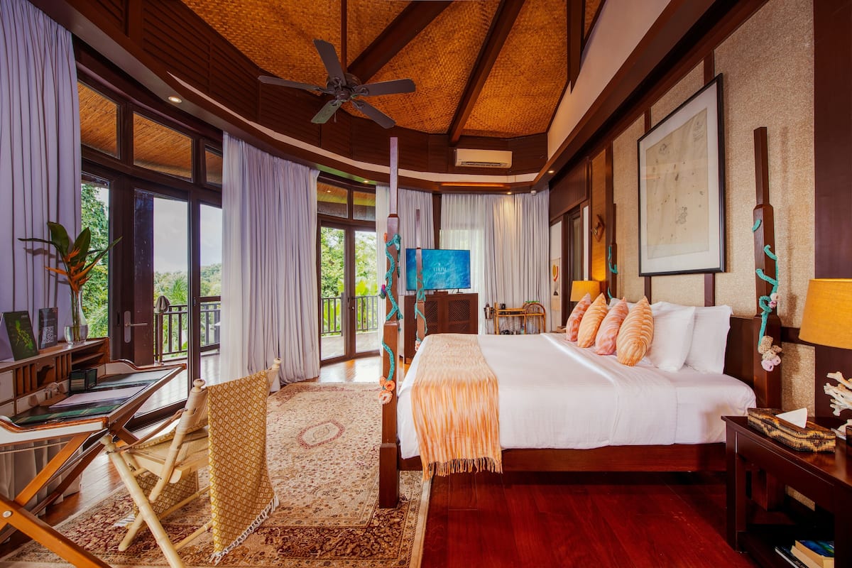 A spacious bedroom with a large bed, a desk, a rocking chair, and a television.