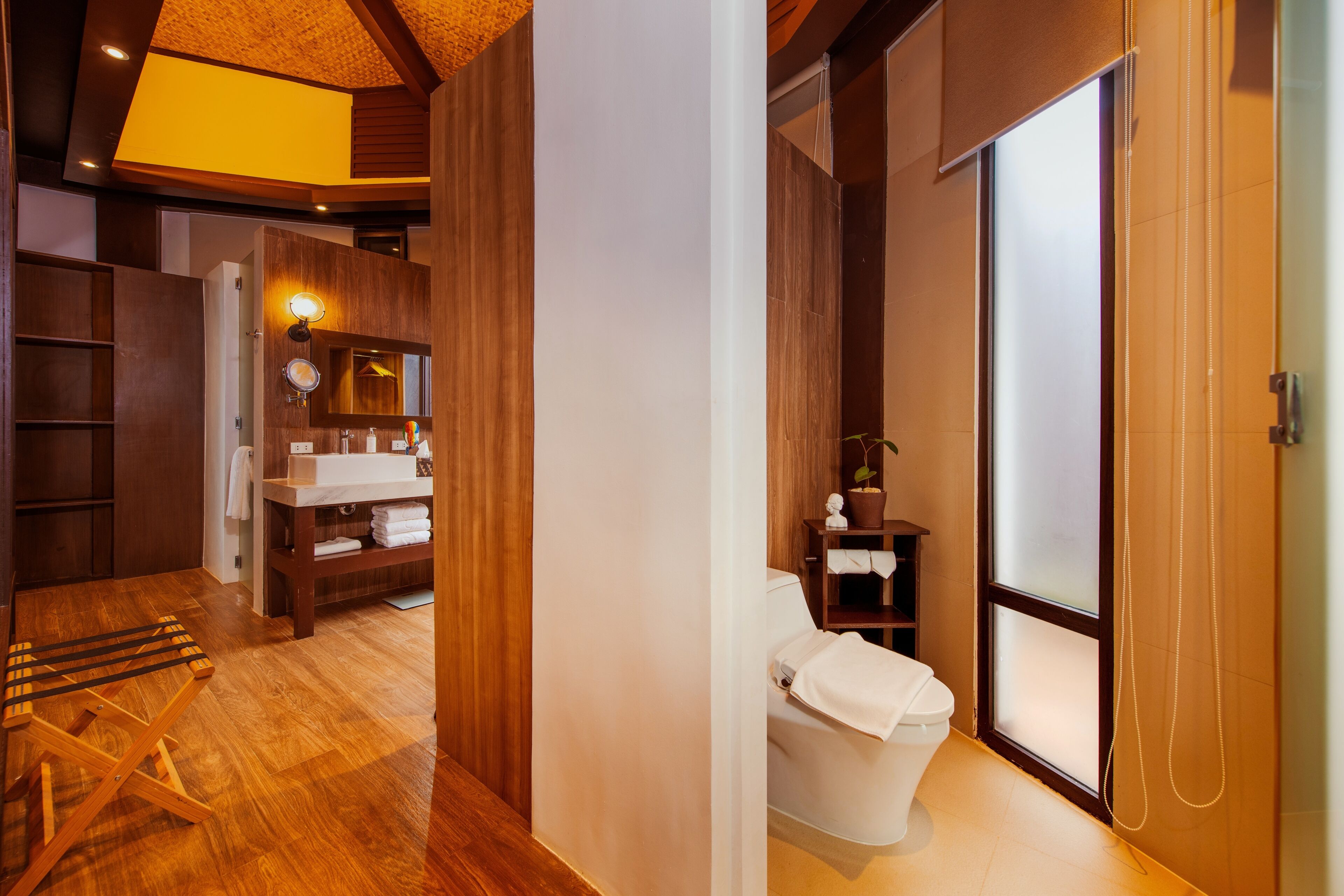 A modern bathroom with a wooden floor, a white toilet, a sink, and a mirror.