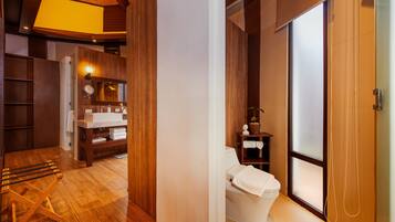 A modern bathroom with a wooden floor, a white toilet, a sink, and a mirror.
