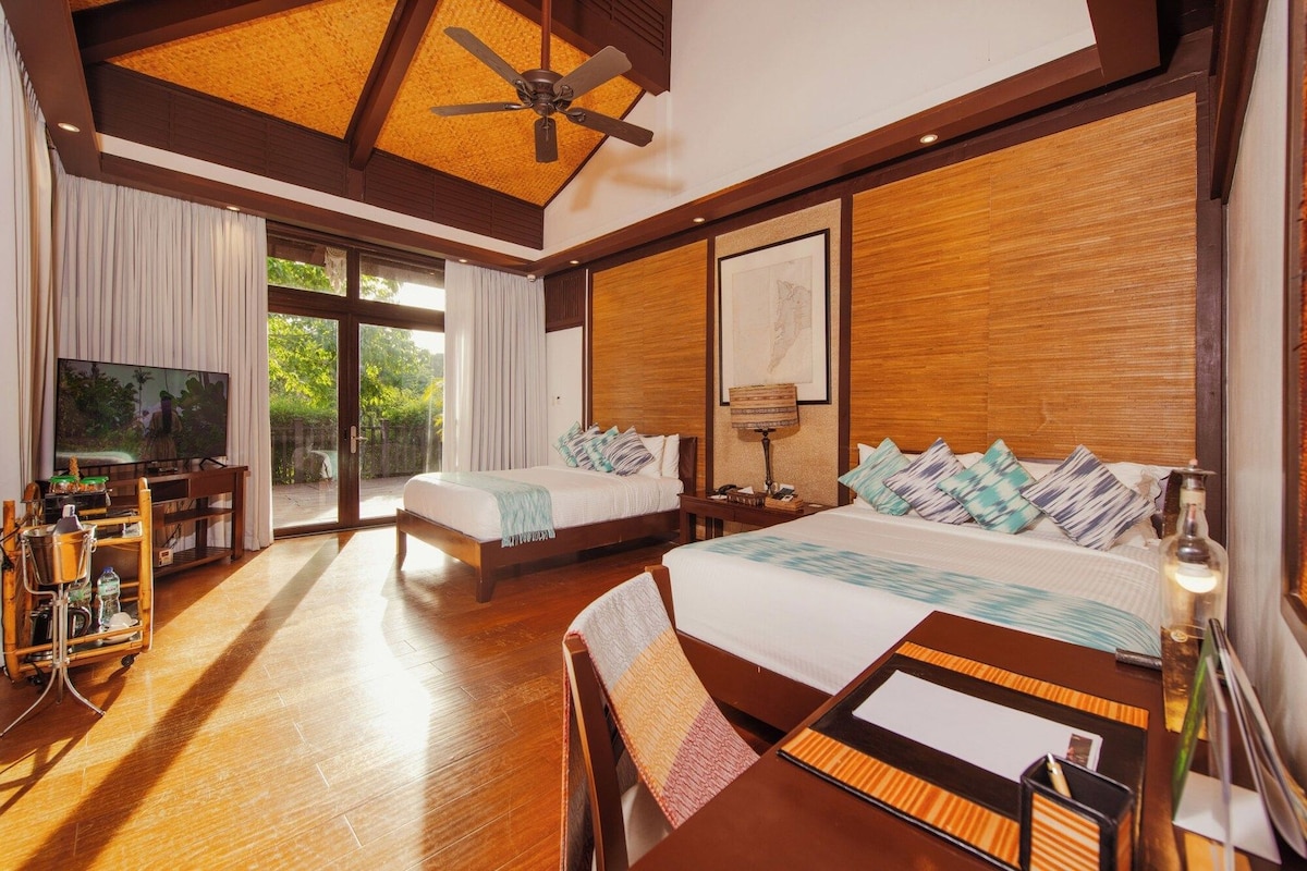 A hotel room with a large bed, a desk, a television, and a ceiling fan.