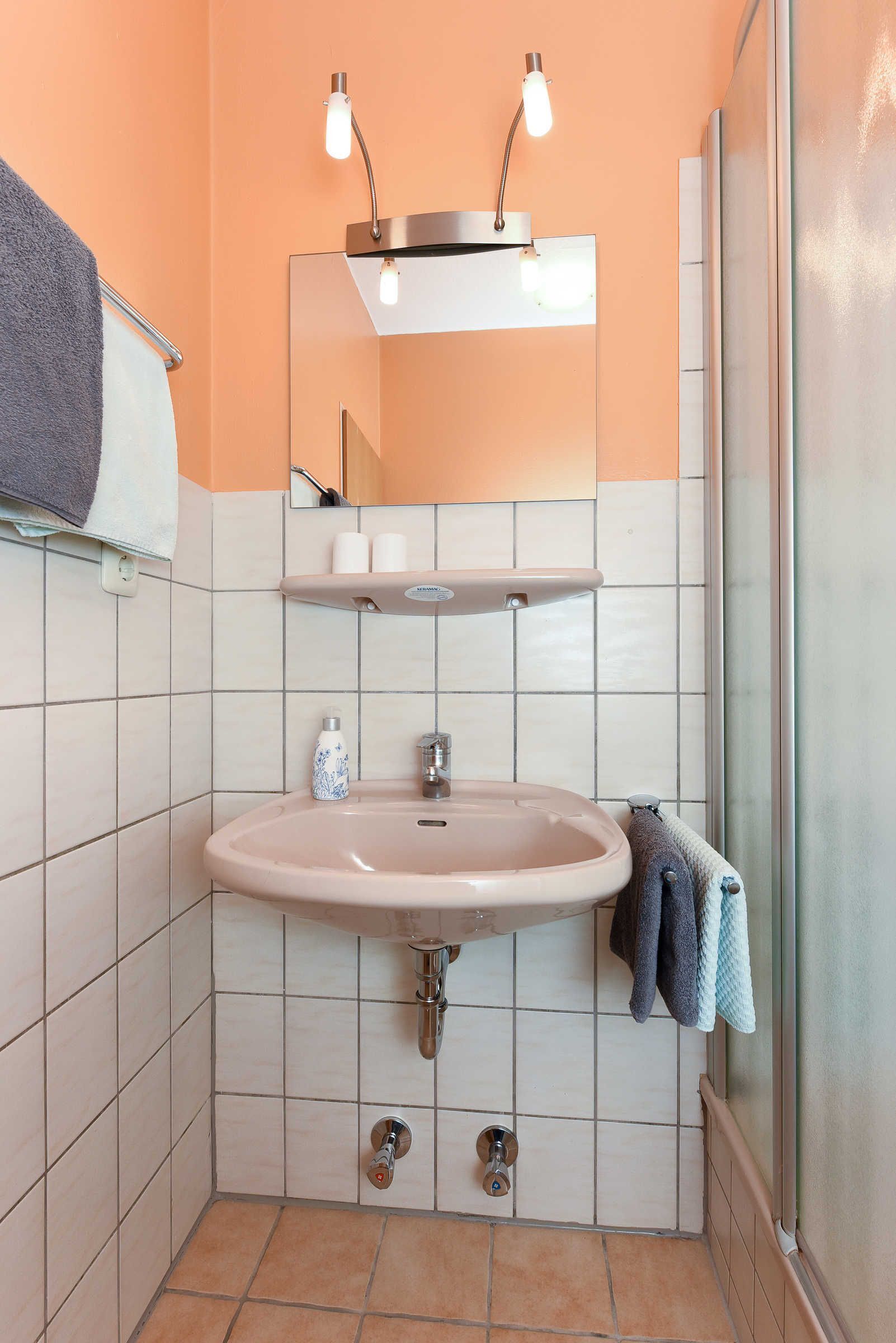 A bathroom with a sink, mirror, towel rack, and shower.