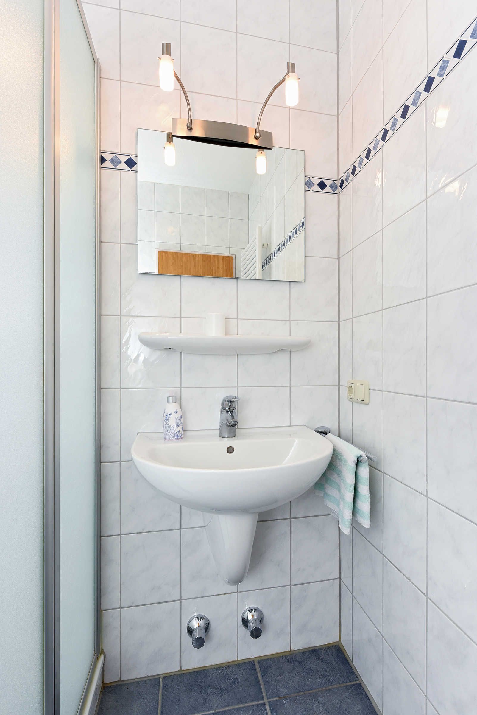 A bathroom with a white sink, mirror, and two wall-mounted lights.