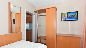 Une chambre d’hôtel avec un lit, une armoire et un téléviseur fixé au mur.