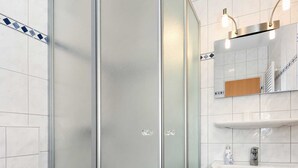 Une salle de bain avec une douche à parois de verre, un lavabo blanc et un miroir au-dessus du lavabo.