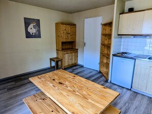 A kitchen with a wooden table, cabinets, and a small stool.