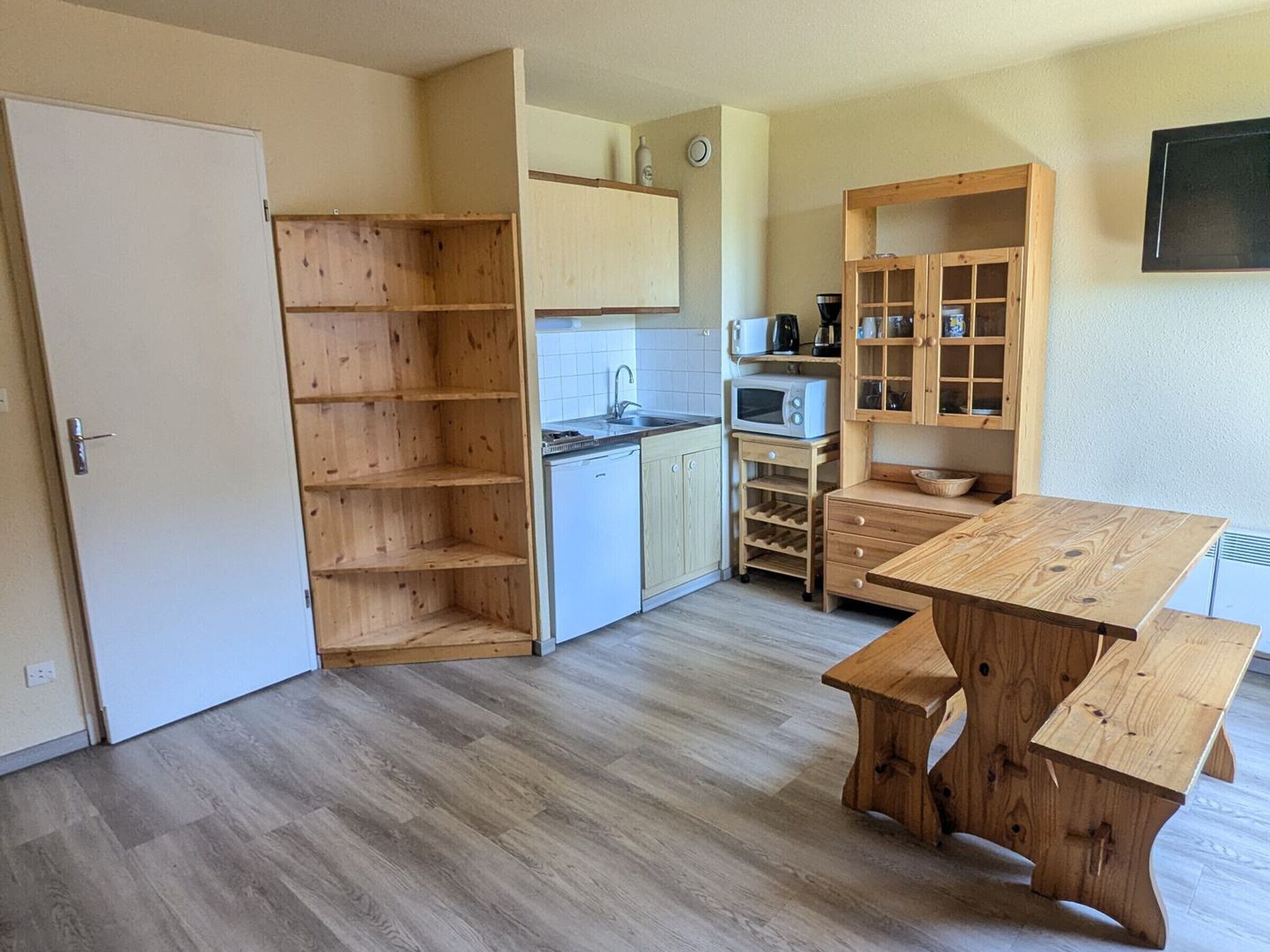 A kitchen with wooden cabinets, a microwave, a sink, and a dining table.