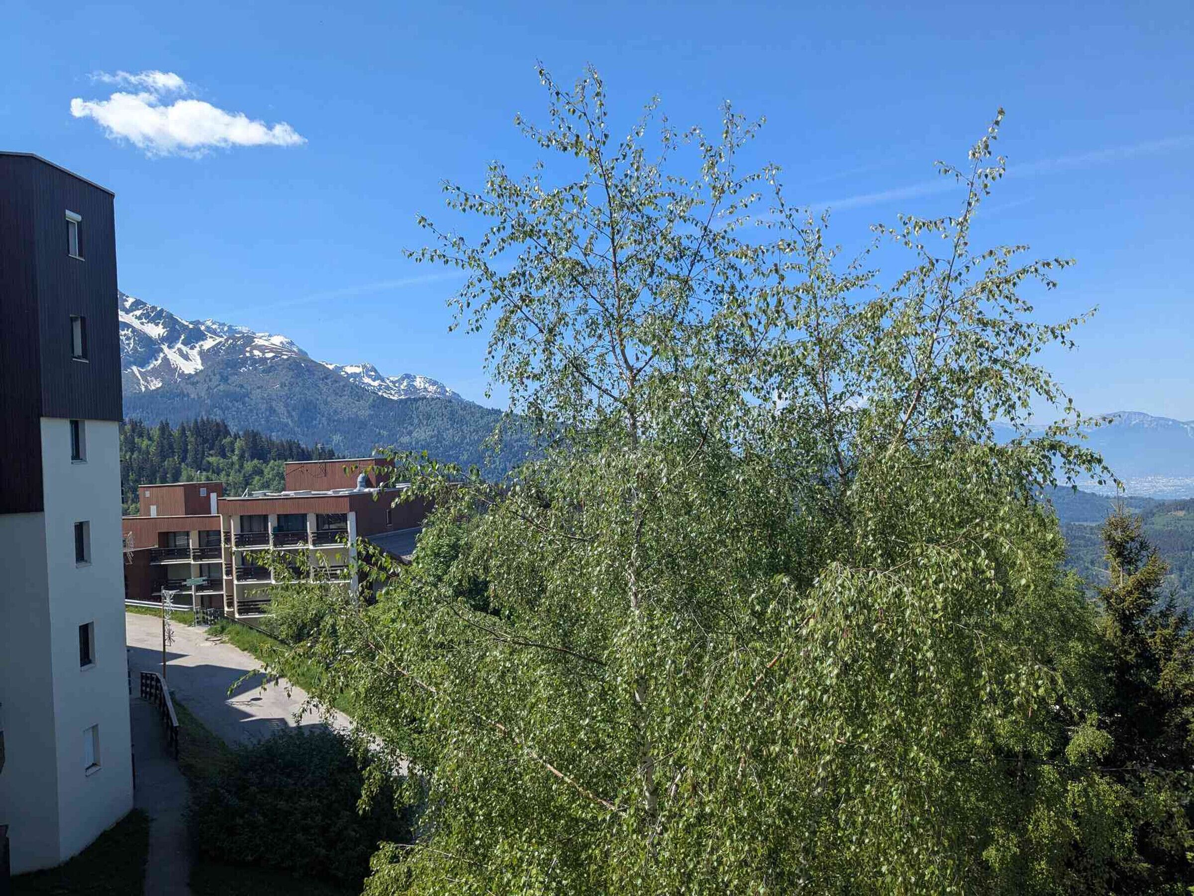 A building with a modern design, a clear view of the mountains, and a tree in the foreground.