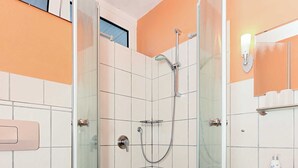 Een badkamer met een douchecabine van glas, een toilet en een wastafel.