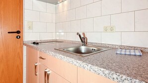 Een keuken met een granieten aanrechtblad, een roestvrijstalen spoelbak en houten kastjes.