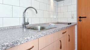 Una cocina con pileta de acero inoxidable, encimera de granito, muebles de madera y extractor de acero inoxidable.