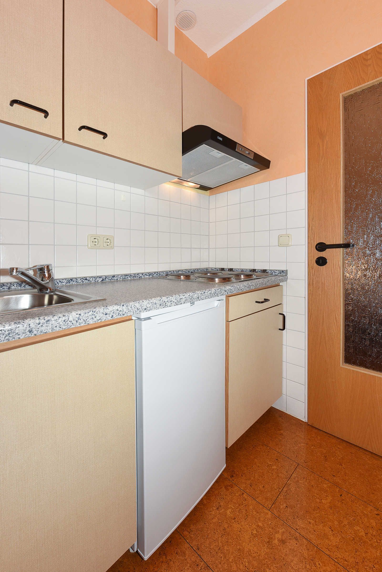 A kitchen with white cabinets, a stainless steel sink, a built-in oven, and a dishwasher.