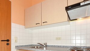 Une cuisine de taille réduite avec des meubles blancs, une cuisinière encastrée et un évier.
