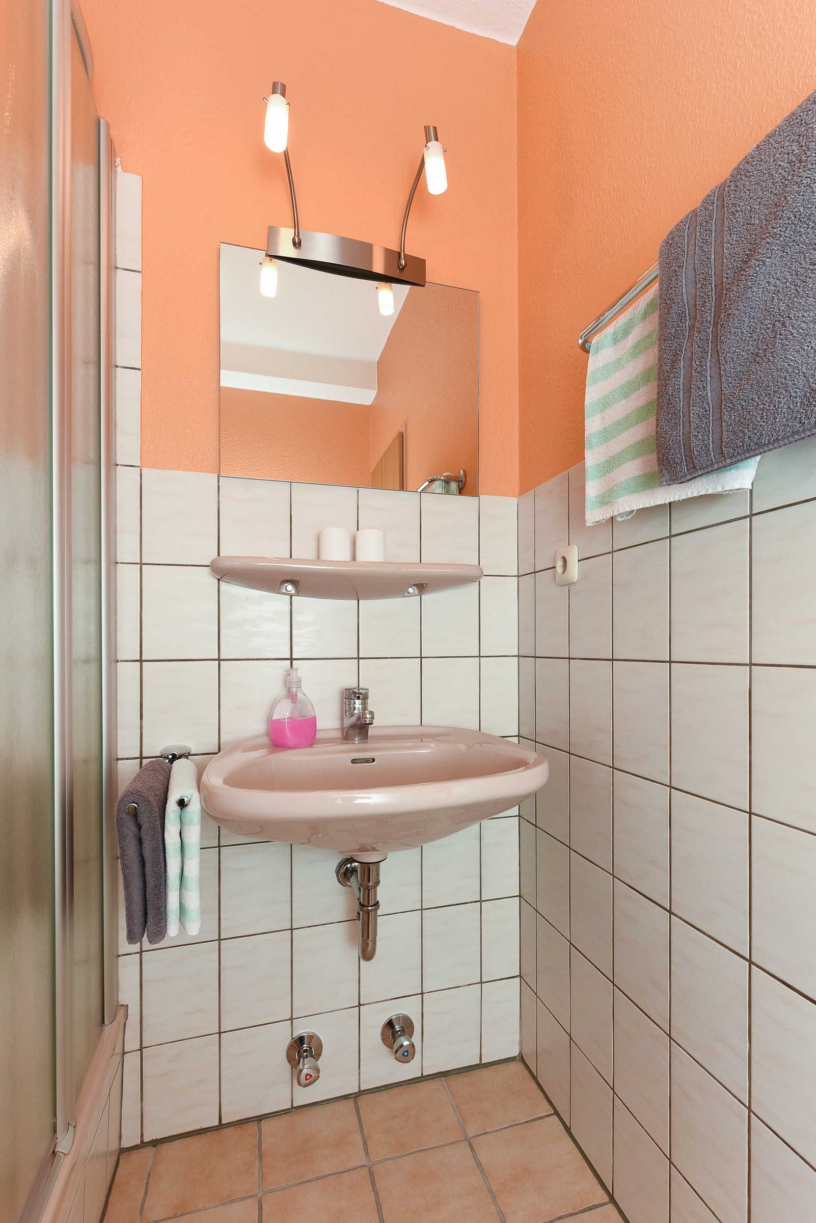 A bathroom with a sink, mirror, and towel rack.