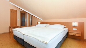 Une chambre à coucher avec un grand lit, une armoire en bois, une petite table et une table de chevet avec une lampe.