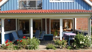 Ein blaues Haus mit verdeckter Veranda, Ziegelmauern und einem roten Ziegeldach.