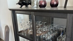 A black glass cabinet with a pig figurine, a vase with flowers, and decorative items.