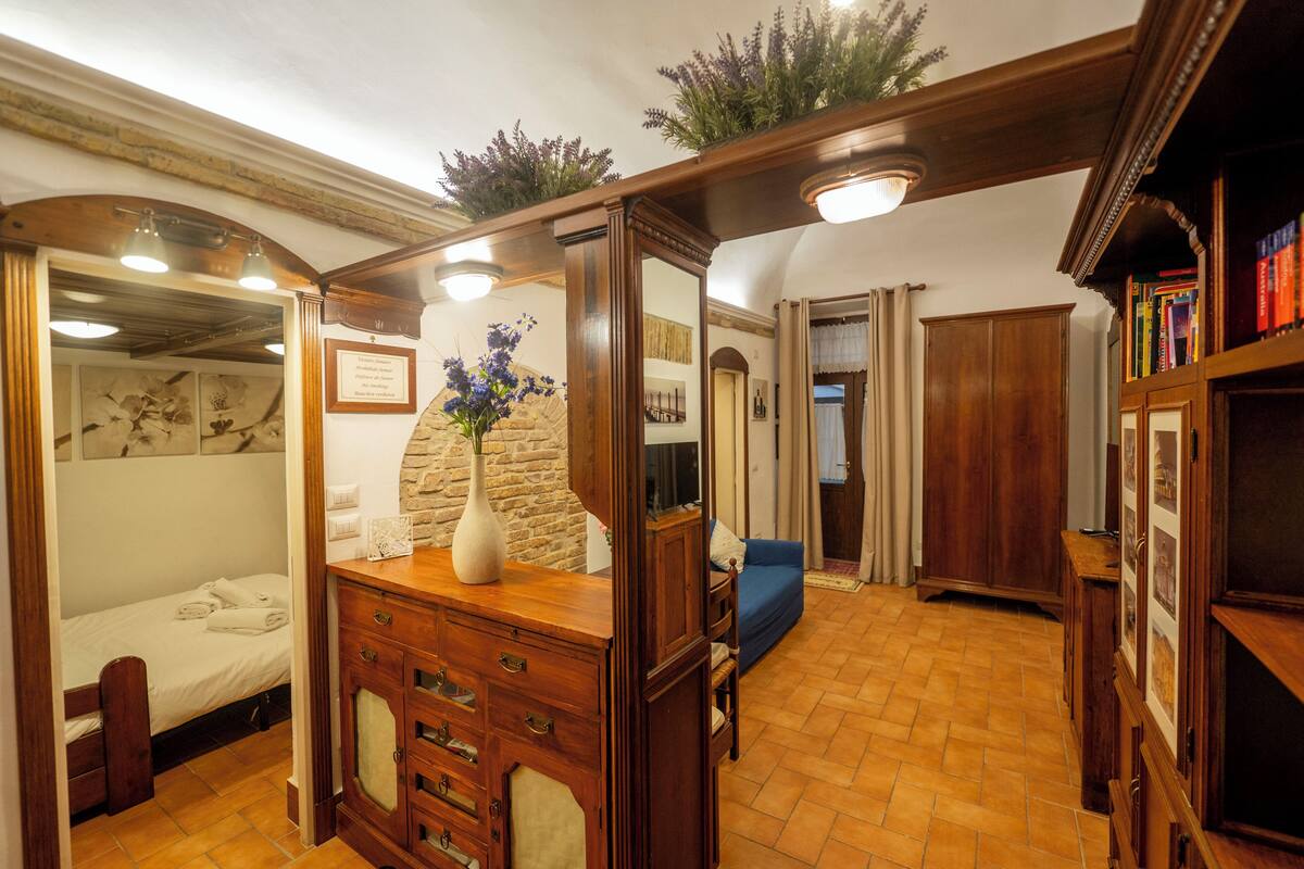 A room with a bed, wooden dresser, and a blue sofa.