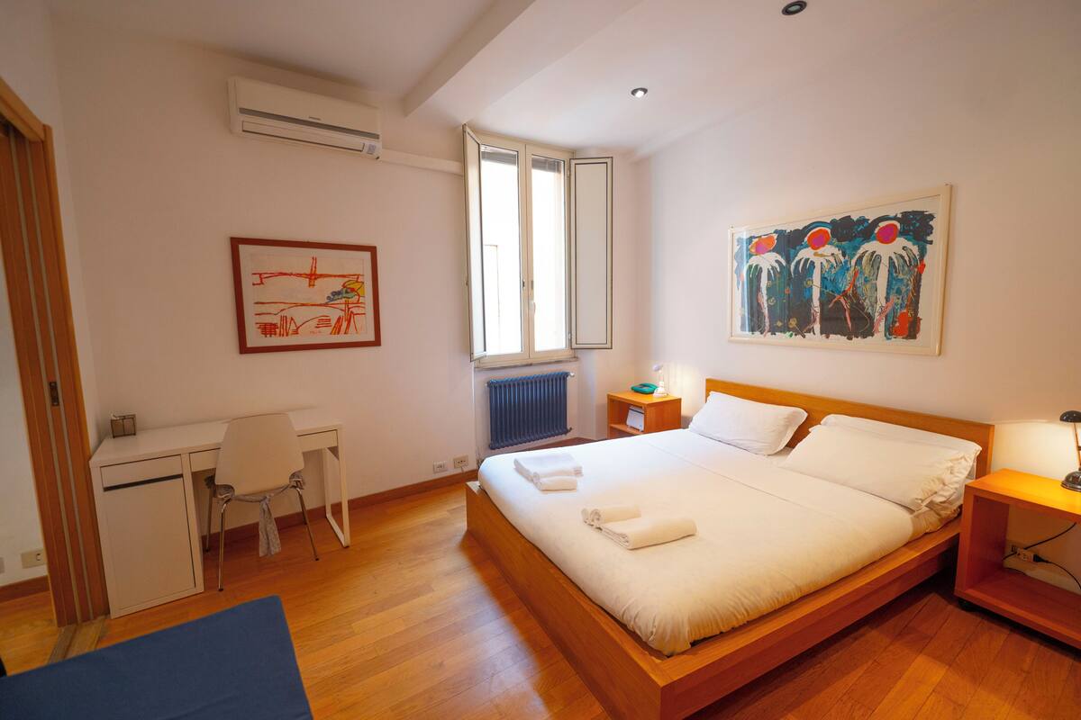 A bedroom with a wooden bed, a desk, and a chair.