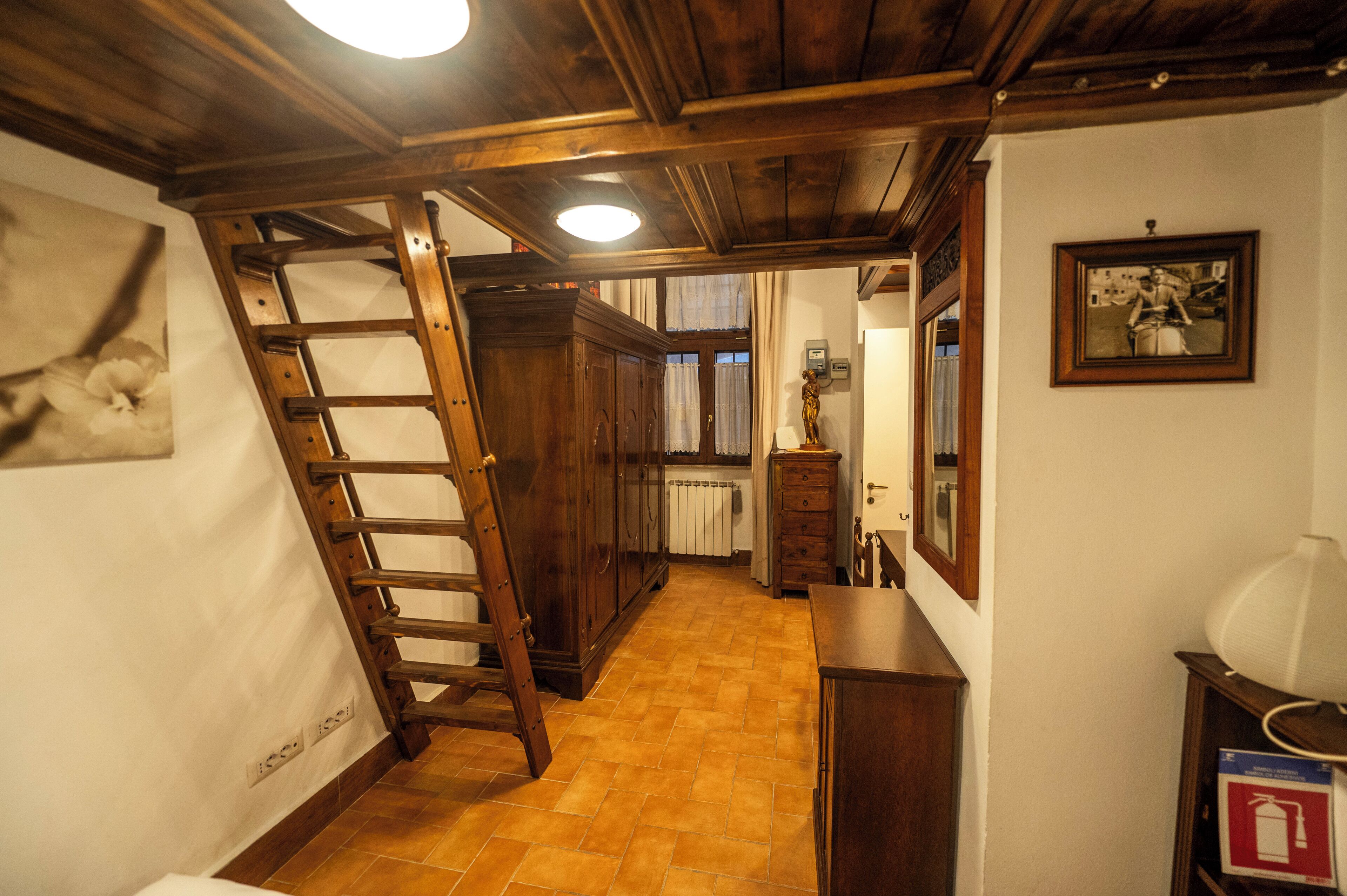 A narrow hallway with a wooden ladder, a radiator, and a framed picture on the wall.