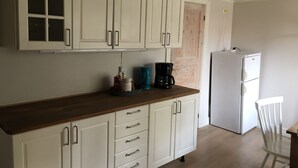 A kitchen with white cabinets, a wooden countertop, a coffee maker, and a refrigerator. - Cozy cottage in the countryside, surrounded by nature (Västra Götalands län)