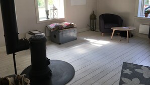 A room with a fireplace, a sofa, a small table, and a window with blinds. - Cozy cottage in the countryside, surrounded by nature (Västra Götalands län)