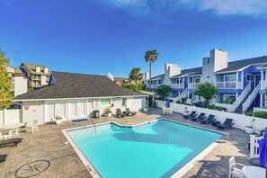 Une piscine avec des chaises longues et un bâtiment à la façade bleue.