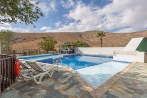 Une piscine dotée de chaises longues, d’une bouée de sauvetage et offrant une vue sur un paysage montagneux.
