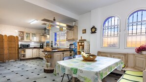 A kitchen with a dining table, chairs, and a window with a view. - Holiday Home “Milestone House” with Pool, Terrace, Balcony, Air Conditioning & Wi-Fi (Rincon de la Vicoria)