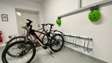 A bicycle parked next to a wall-mounted bike rack with helmets hanging above.