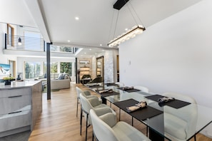 Une cuisine spacieuse et moderne avec un coin repas, dotée d’un plafond haut, d’appareils électroménagers intégrés et offrant une vue sur l’extérieur.