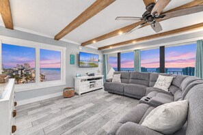 A modern living room with a large gray sectional sofa, a white entertainment unit, and a ceiling fan.