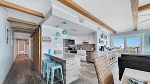 A spacious kitchen with a large island, wooden beams, and a view of the city. - Island Winds East 401 | Gulf Front Walk to HangOut | Beach Getaways (Gulf Shores)