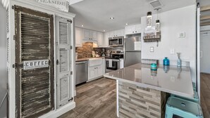 Une cuisine moderne avec des meubles blancs, un pare-feu en bois, des appareils en acier inoxydable et un élément décoratif de couleur turquoise.