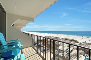 Ein Balkon mit Blick auf einen Strand, einen Poolbereich und eine Treppe.