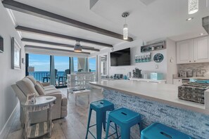 A modern kitchen with a large island, bar stools, and a view to the outside.