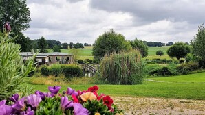 A rural landscape with a wooden structure, a bridge, and a field.