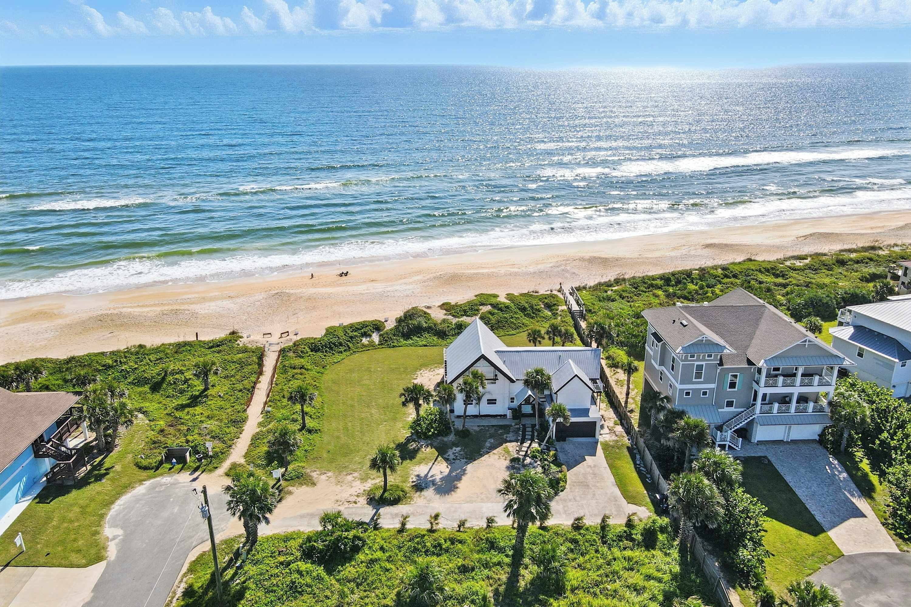 Une propriété située en bord de mer, comprenant une grande maison, une piscine et une pelouse bien entretenue.