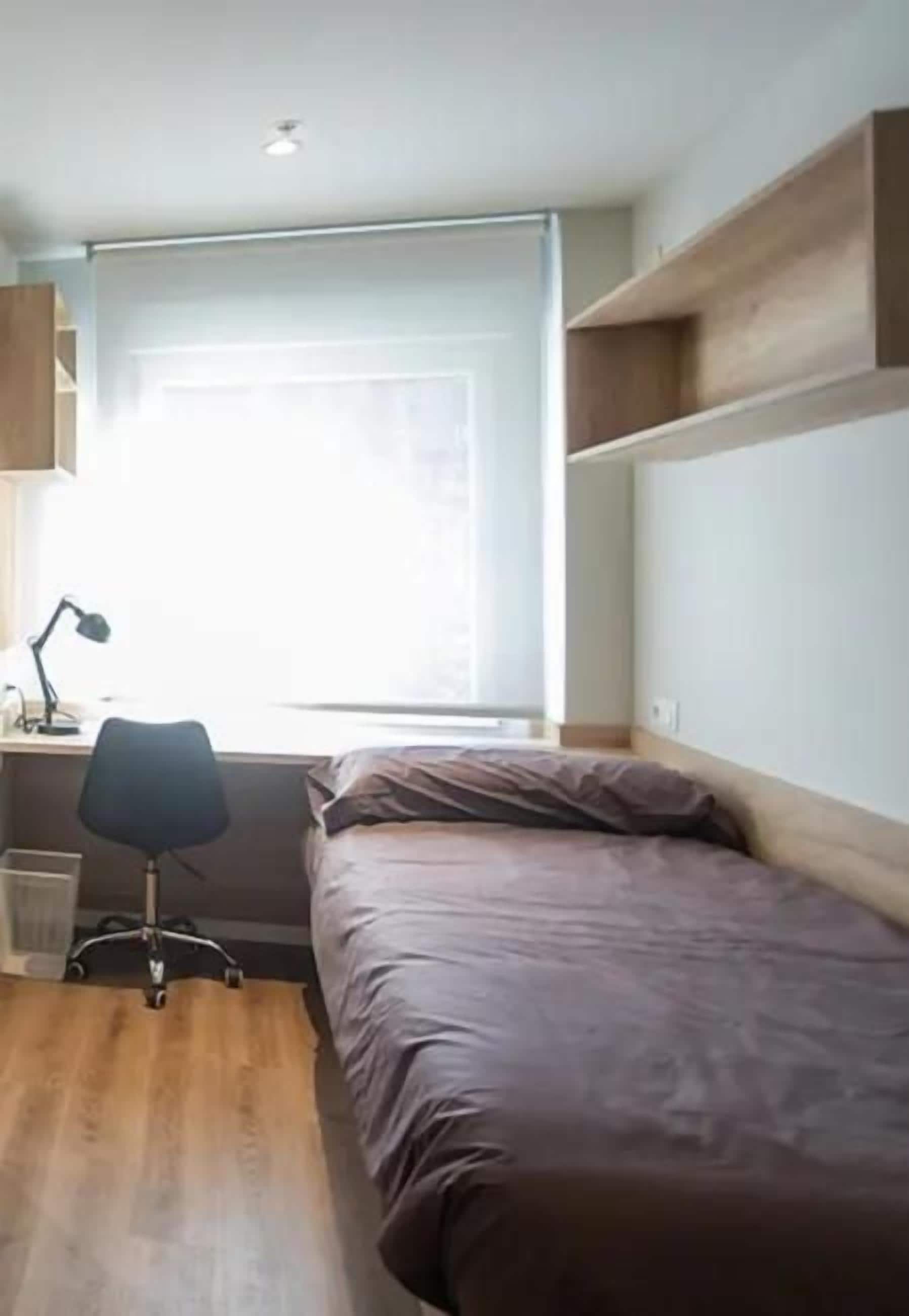 Un dormitorio con una cama, un escritorio y una silla.