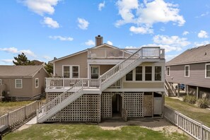 A two-story house with a balcony, a staircase, and a designated shower area. - 5212A- Cotton's Cabana - Sunny KDH Retreat Near Beach Access (Kill Devil Hills)