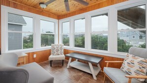 Une véranda avec de grandes fenêtres, un ventilateur de plafond et un intérieur en bois.