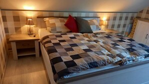 Ein Schlafzimmer mit kariertem Bettbezug, zwei Nachttischen mit Lampen und einem Beistelltisch.