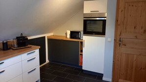 Eine kleine Küche mit Mikrowelle, Backofen und einer Holztür.