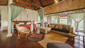 Una habitación amplia con techo de madera, un conjunto de sofás, una mesa de comedor y un gran ventanal con cortinas.