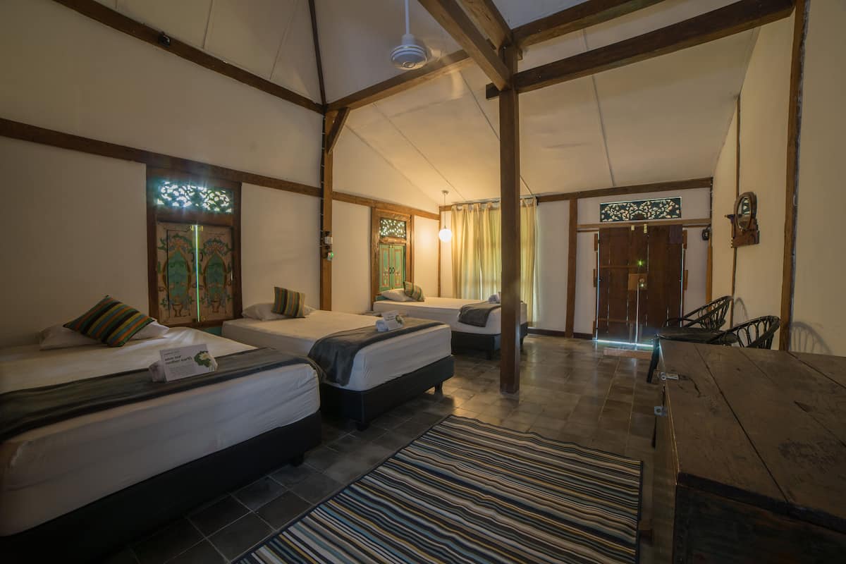 A hotel room with two beds, a wooden table, and a view of the outside.