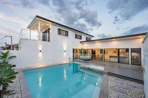 A modern house with a swimming pool, a covered patio, and a dining area. - REEF Luxury Home, Ocean View, Large Pool & Hot Spa (Anna Bay)