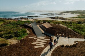 A coastal landscape with a paved walkway leading to a viewing platform overlooking the ocean. - REEF Luxury Home, Ocean View, Large Pool & Hot Spa (Anna Bay)