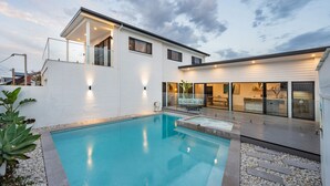 Una casa moderna con piscina, un porche cubierto y un comedor.