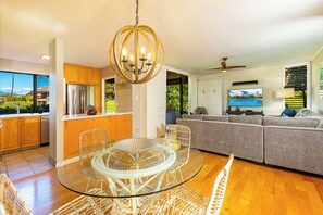 Una cocina moderna con refrigerador de acero inoxidable, gabinetes de madera y una mesa de comedor de vidrio con sillas.
