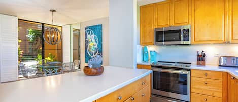 A modern kitchen with wooden cabinets, stainless steel appliances, and a large island with a bowl.