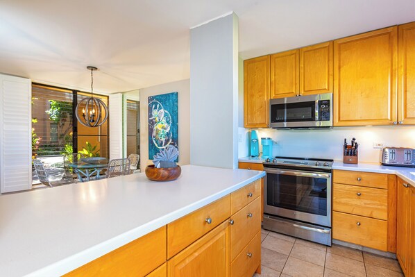 A modern kitchen with wooden cabinets, stainless steel appliances, and a large island with a bowl.
